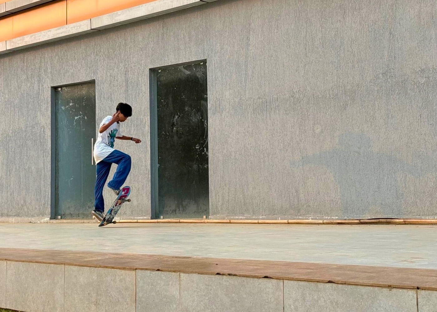 A youth showcasing his skateboarding skills on a concrete pavement