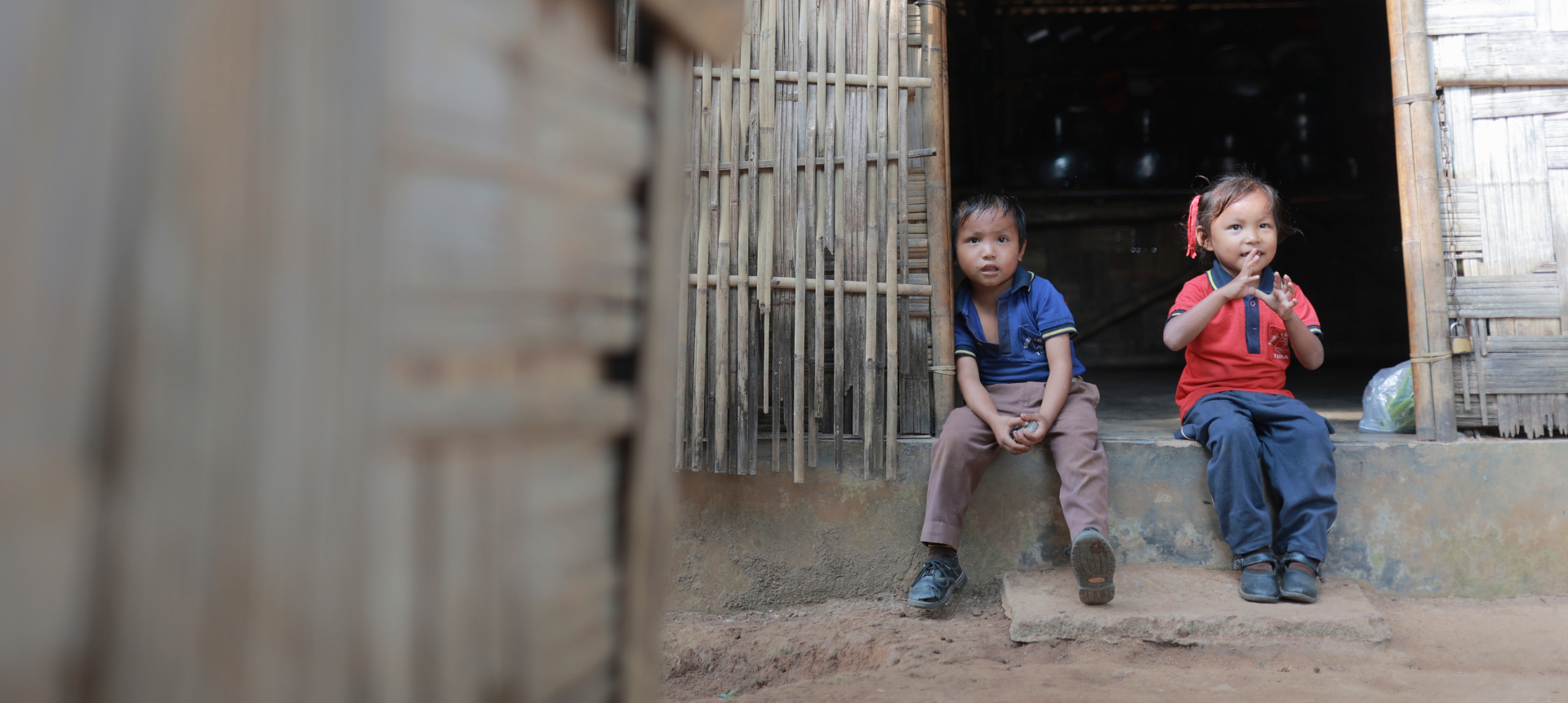 Children sitting at a village home entrance